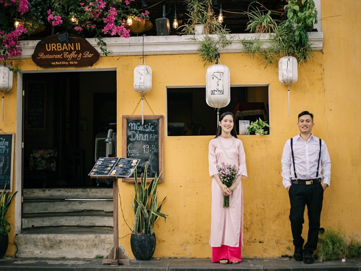 Áo dài kết hợp cùng nón lá là lựa chọn kinh điển giúp tô điểm vẻ đẹp truyền thống và hòa quyện với bối cảnh cổ kính của Hội An.