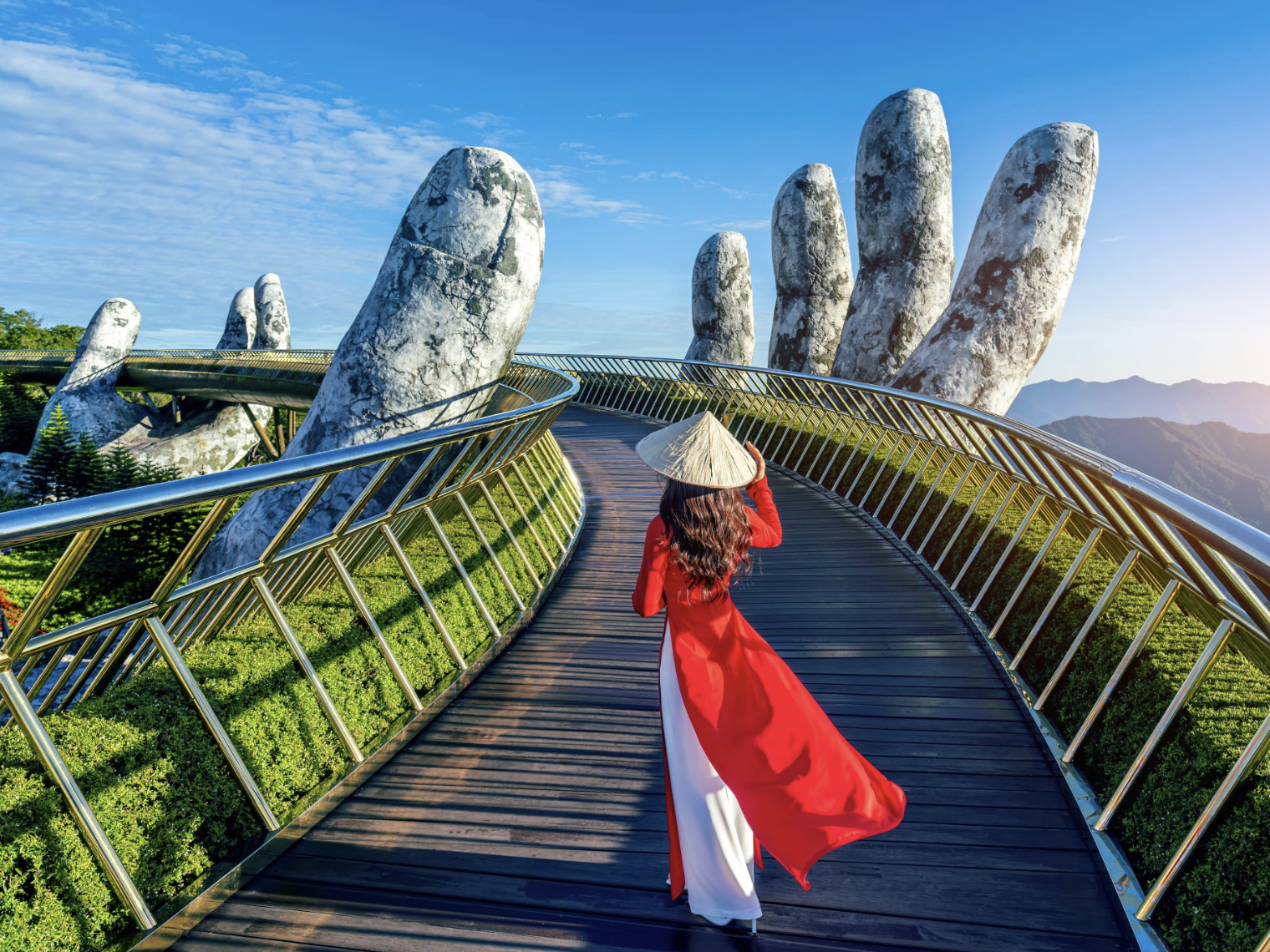 Áo dài đỏ nổi bật tại Cầu Vàng Bà Nà Hills, tạo điểm nhấn ấn tượng giữa không gian mây núi bồng bềnh.